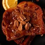 Pieces of brioche french toast on a black plate. Topped with pecans.