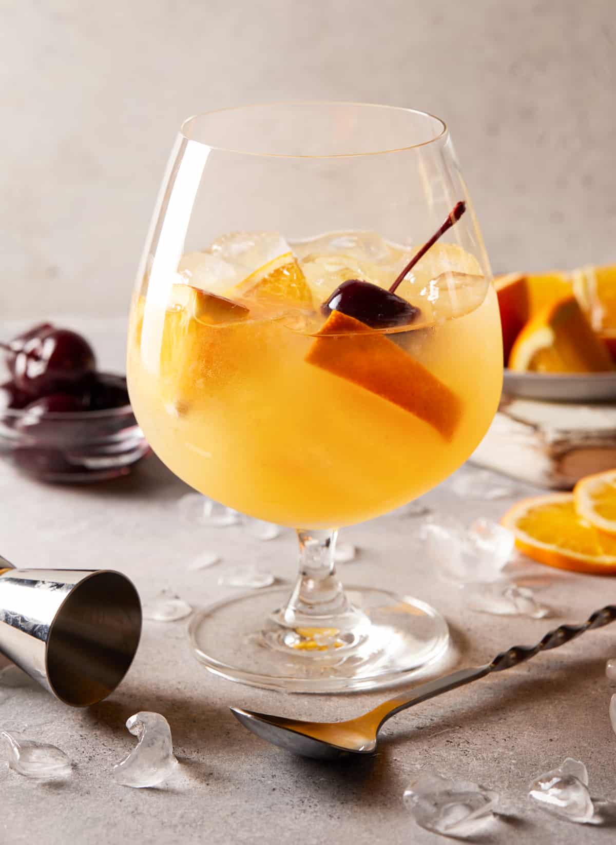 Amaretto orange juice drink in a cocktail glass with cherries and orange slices. 