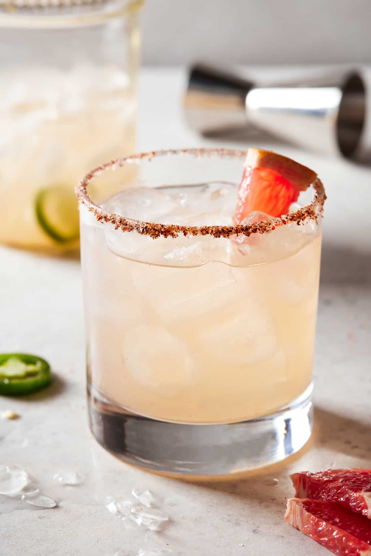 Grapefruit margarita in a low ball glass filled with ice and a garnished with a grapefruit wedge. 