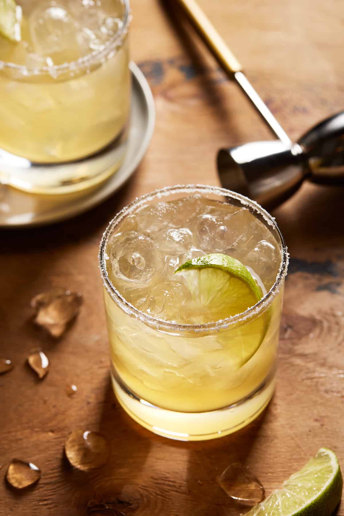 Lowball margarita glass with salted rim and lime wedge. 