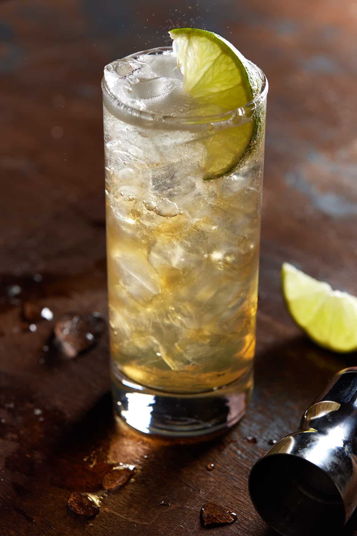 Whiskey and ginger ale in a highball glass filled with ice and garnished with a lime wedge. 