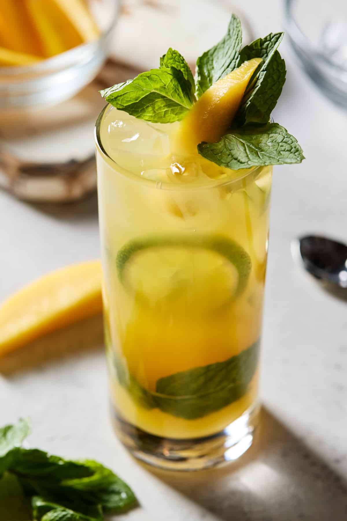 Mango mojito in high ball glass with mint and fresh mango.