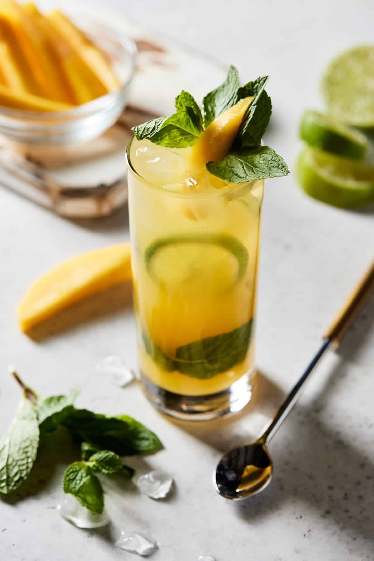 Mango mojito in highball with fresh mint and fresh mango slices.