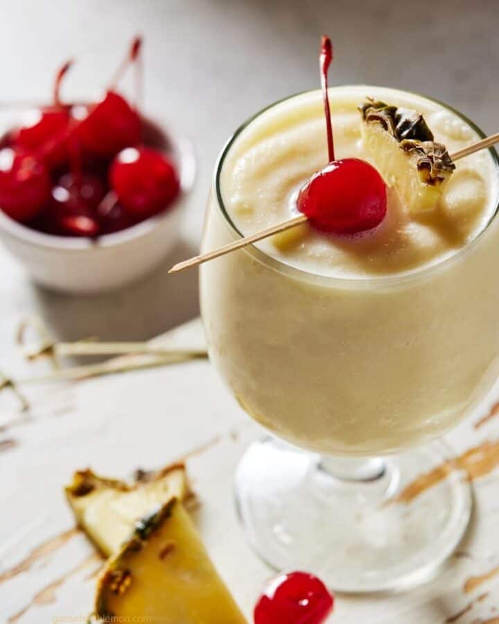 Virgin Piña Colada in a glass garnished with pineapple wedge and maraschino cherry.