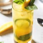 Mojito in high ball with fresh mint and mango slices.