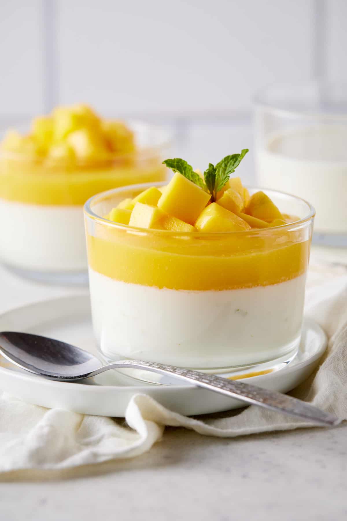 Two glass ramekins filled with mango panna cotta. 