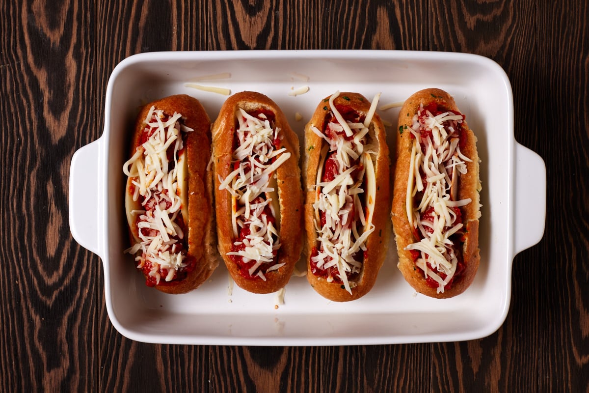 Meatball subs assembled in a white casserole dish. 