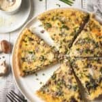 Sliced quiche on plate with fresh chives.
