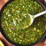 Bowl of herby green sauce with spoon for serving.