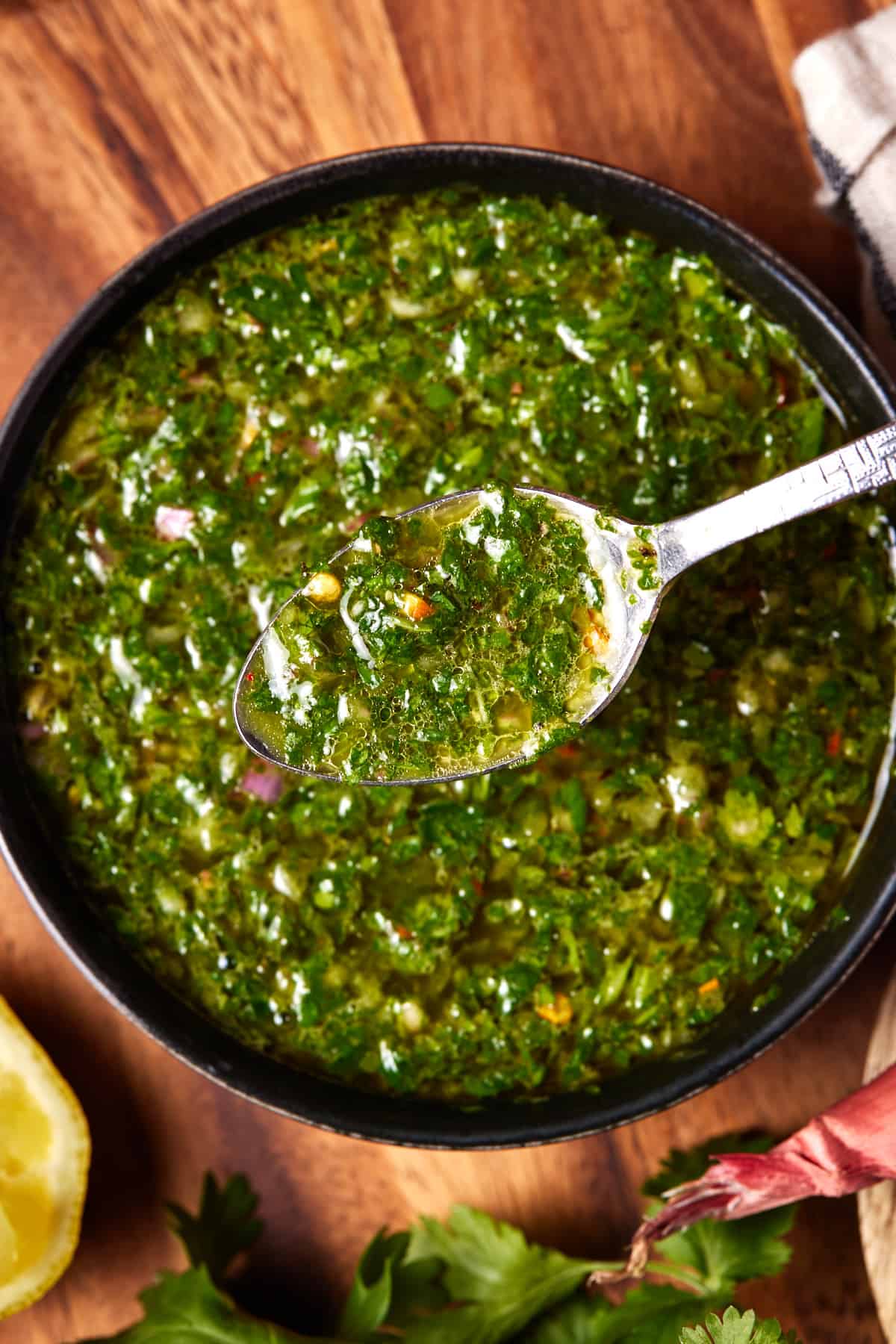 Chimichurri sauce in bowl with crushed red pepper and fresh herbs.