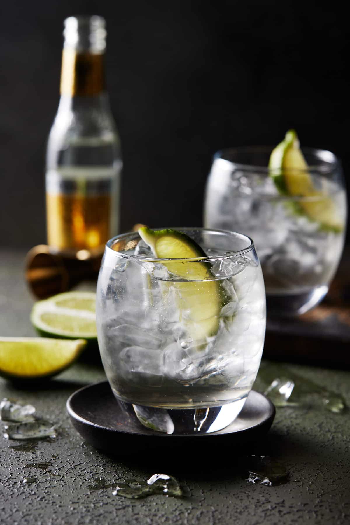 Lowball glasses filled with Elderflower Gin & Tonic cocktails on a green board. 