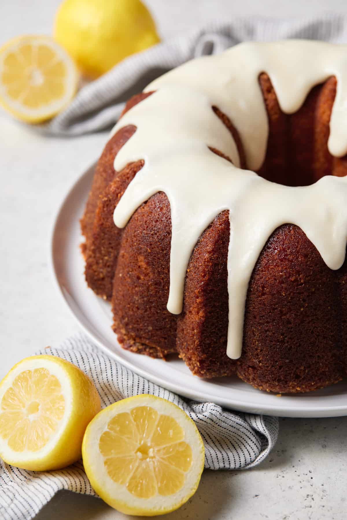 Lemon bundt cake drizzled with icing on a white plate. 