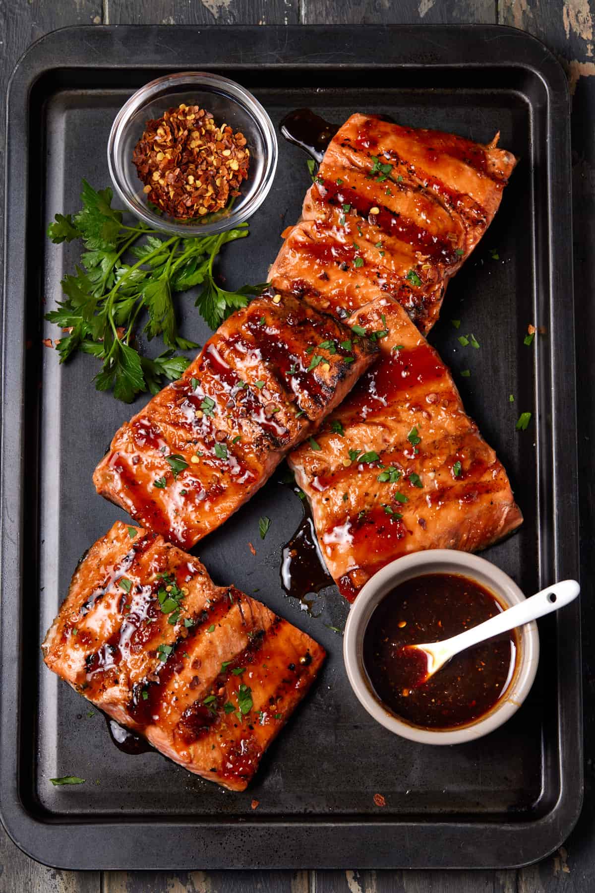 Grilled sockeye salmon fillets on a dark sheet pan.