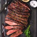 Sliced flank steak on board with salt and pepper.