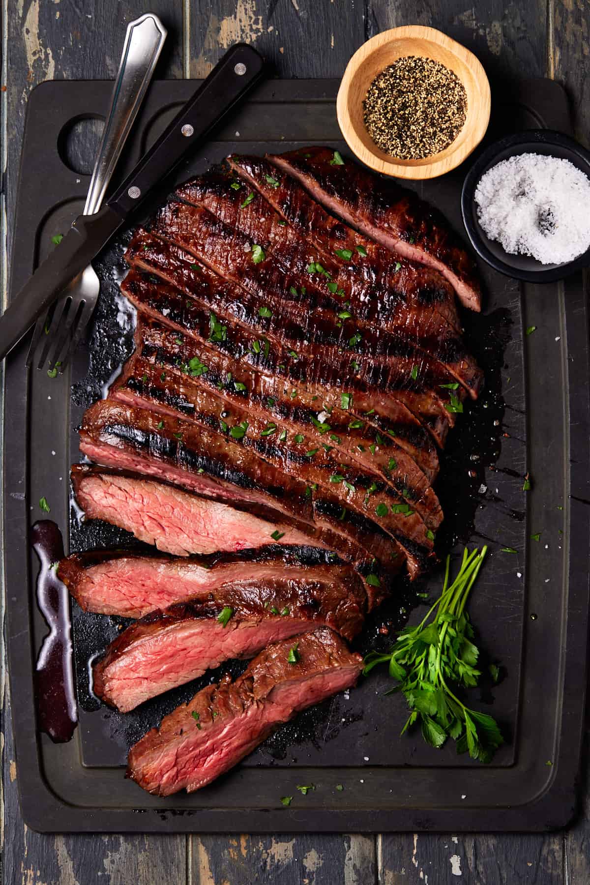Sliced flank steak on tray with fresh parsley.