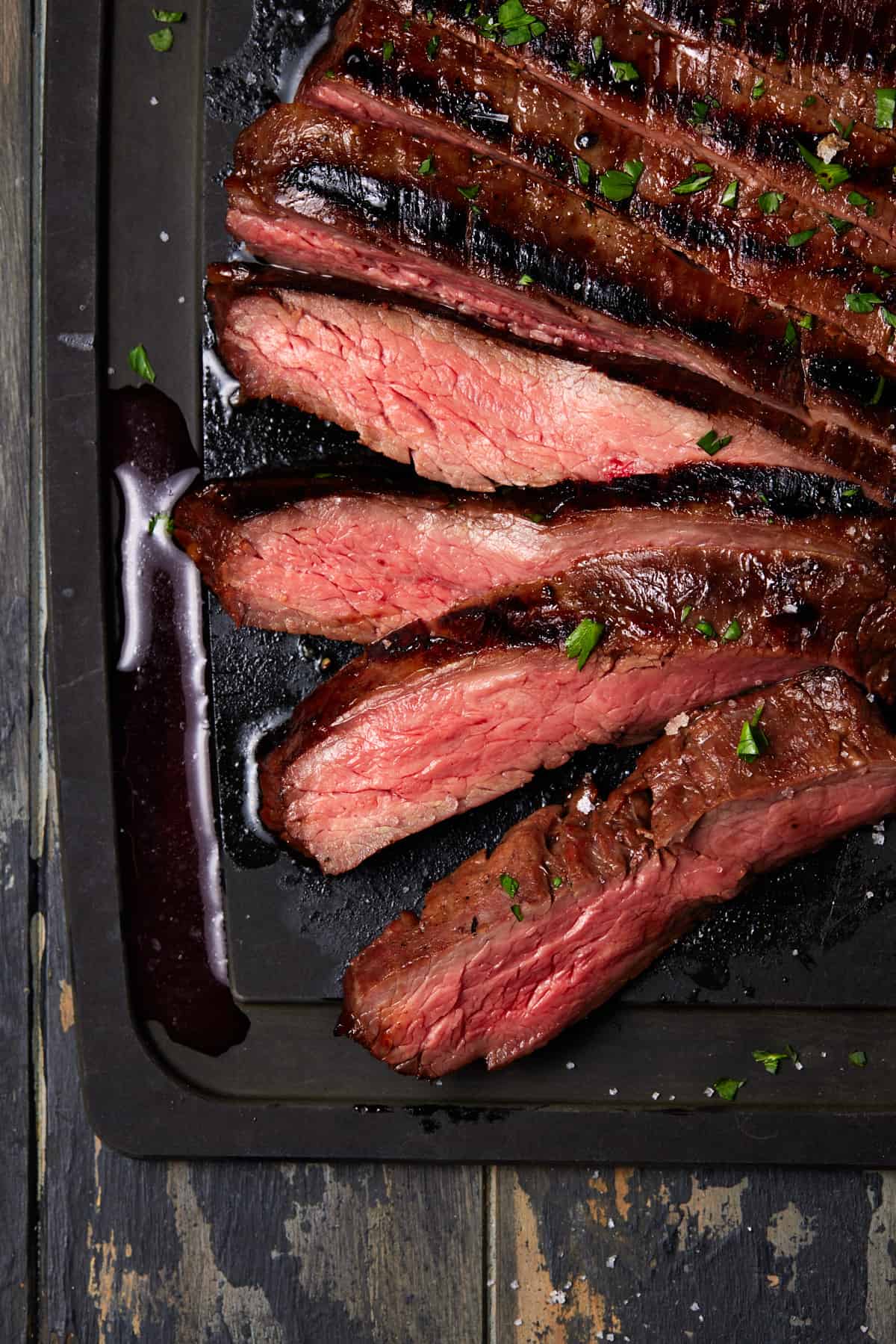 Sliced medium rare flank steak on board.