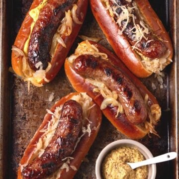 grilled brats in buns with sauerkraut.