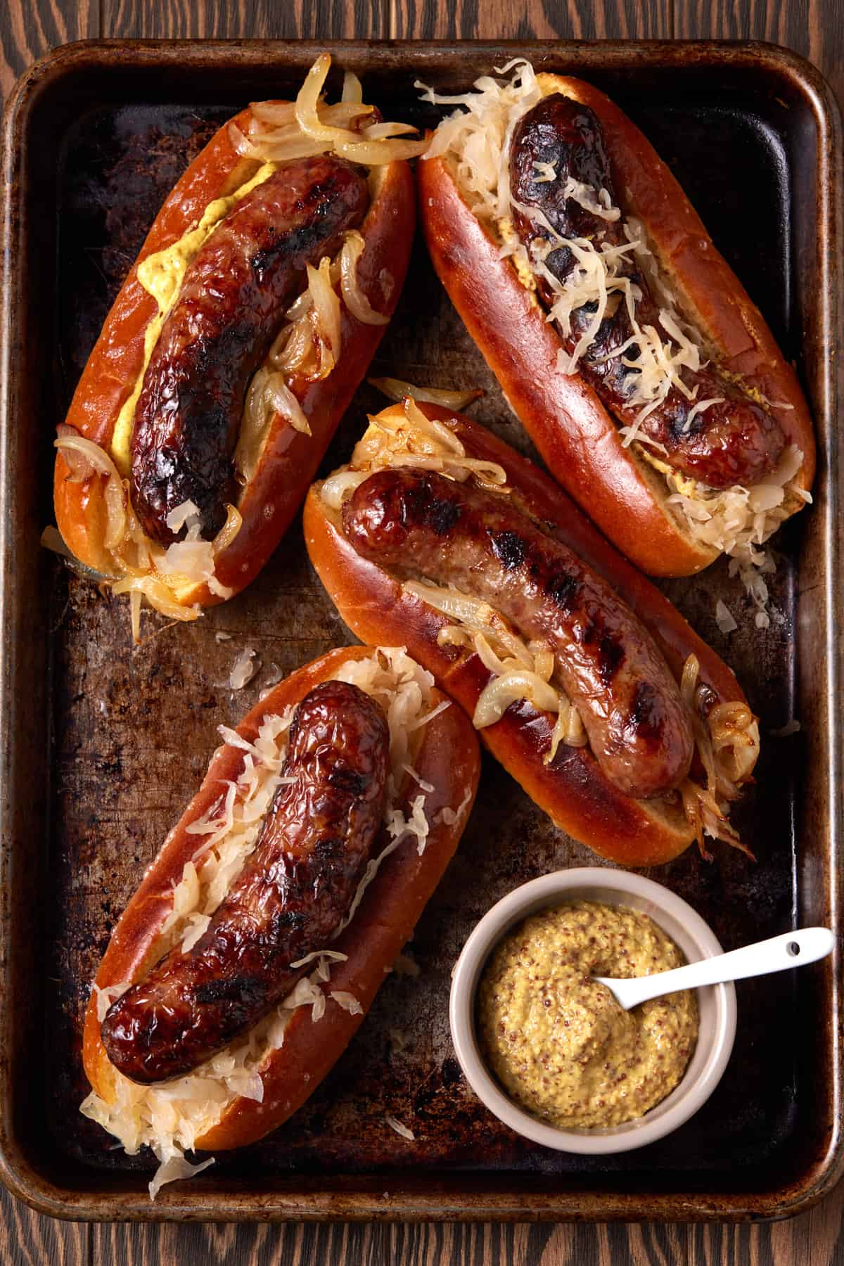 Grilled brats in buns on sheet pan.