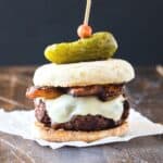 cheeseburger on parchment with a pickle.