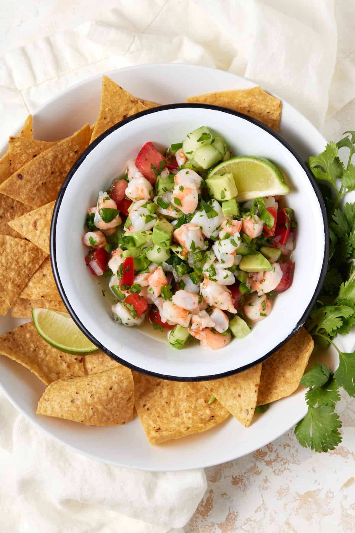 Bowl of shrimp ceviche with tortilla chips and lime wedges. 