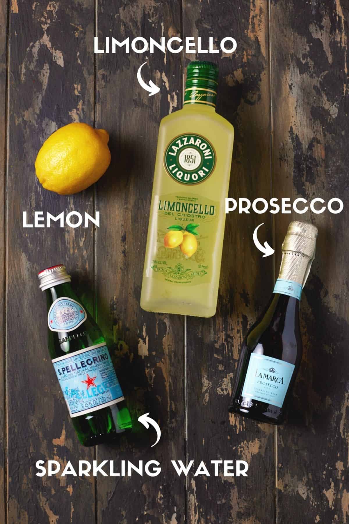 Bottles of limoncello, Prosecco, sparkling water and a lemon on a wood board. 