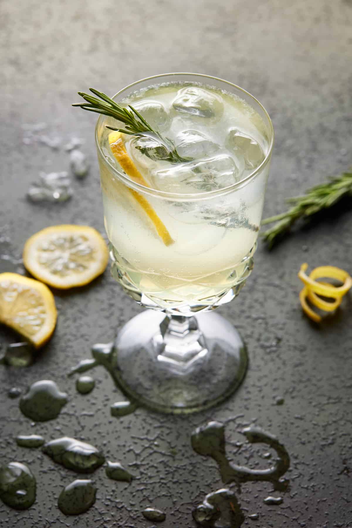Tall footed glass filled with limoncello spritz, lemon slices and fresh rosemary. 