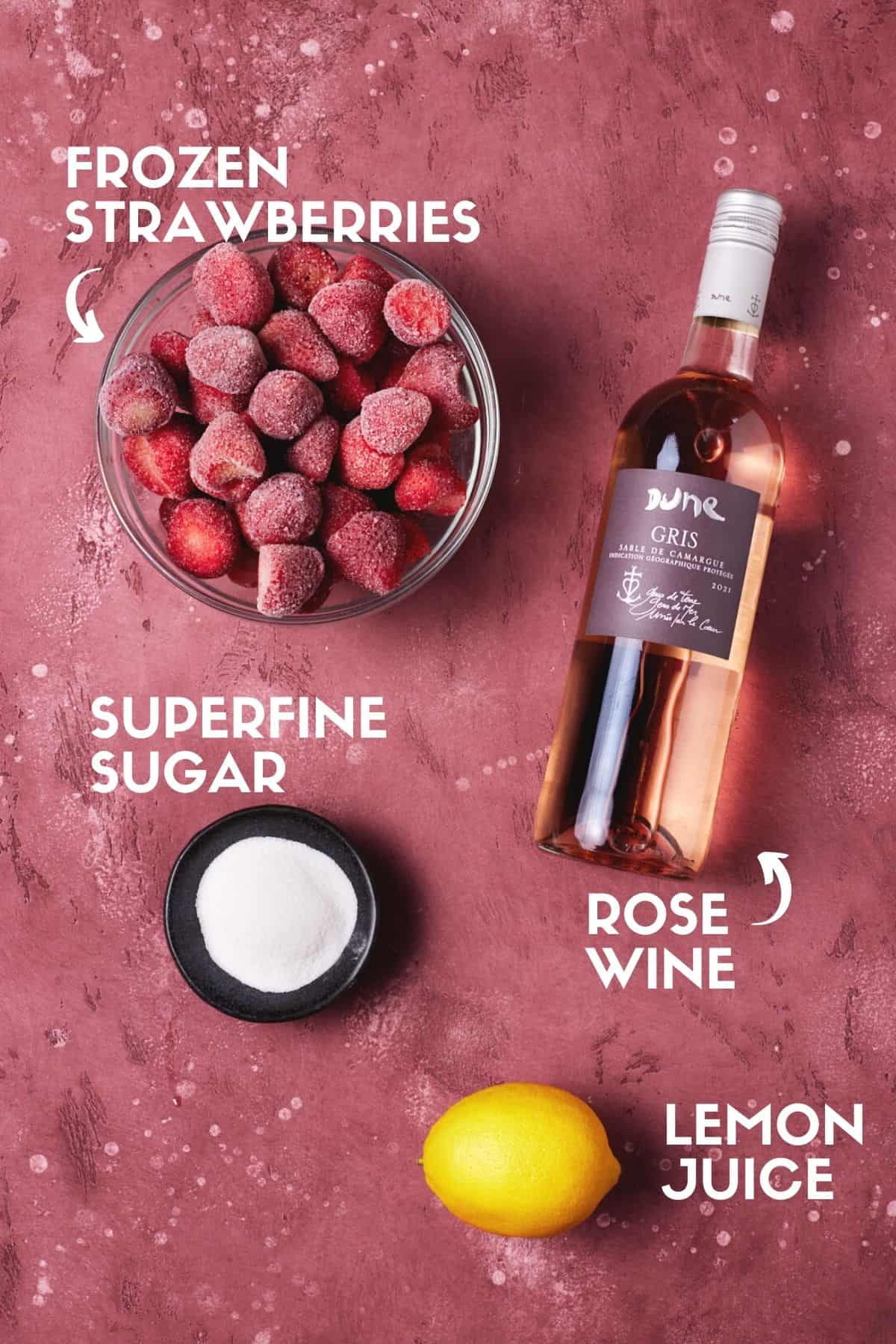 Bottle of rosé, lemon, sugar and frozen strawberries to make Frozen Rosé.