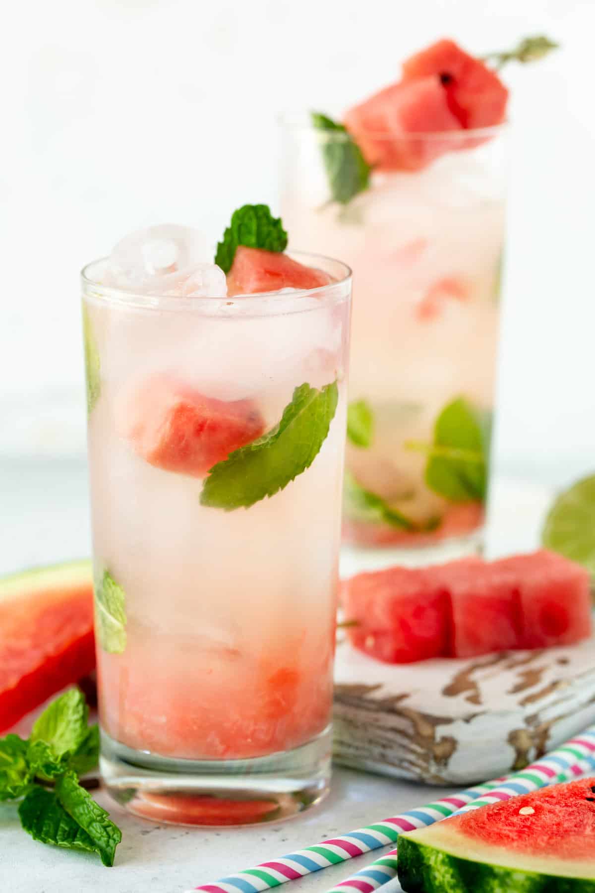 Two glasses of watermelon mojitos on a white board. 