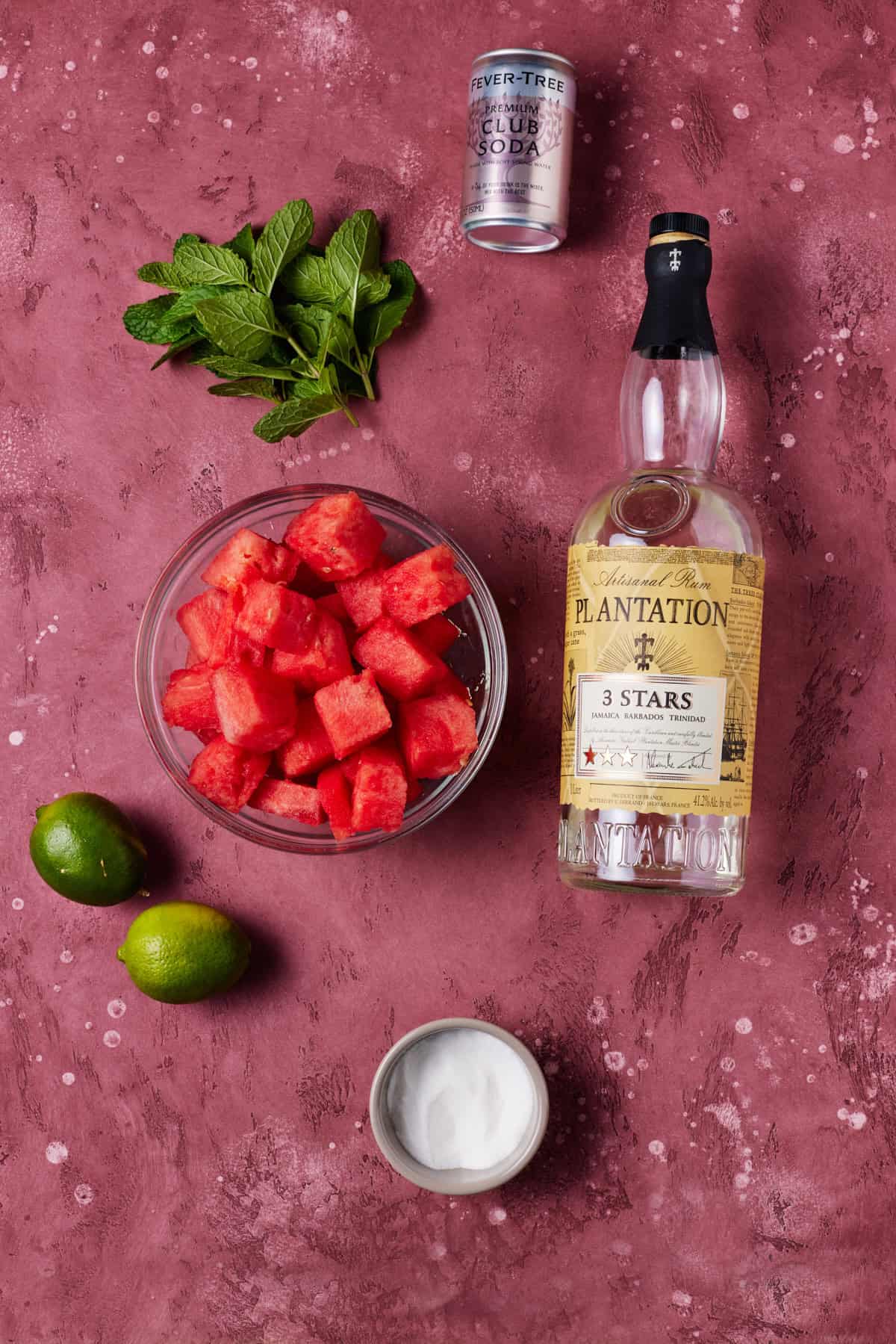 Ingredients needed to make watermelon mojitos, including fresh watermelon, rum, lime juice and club soda.