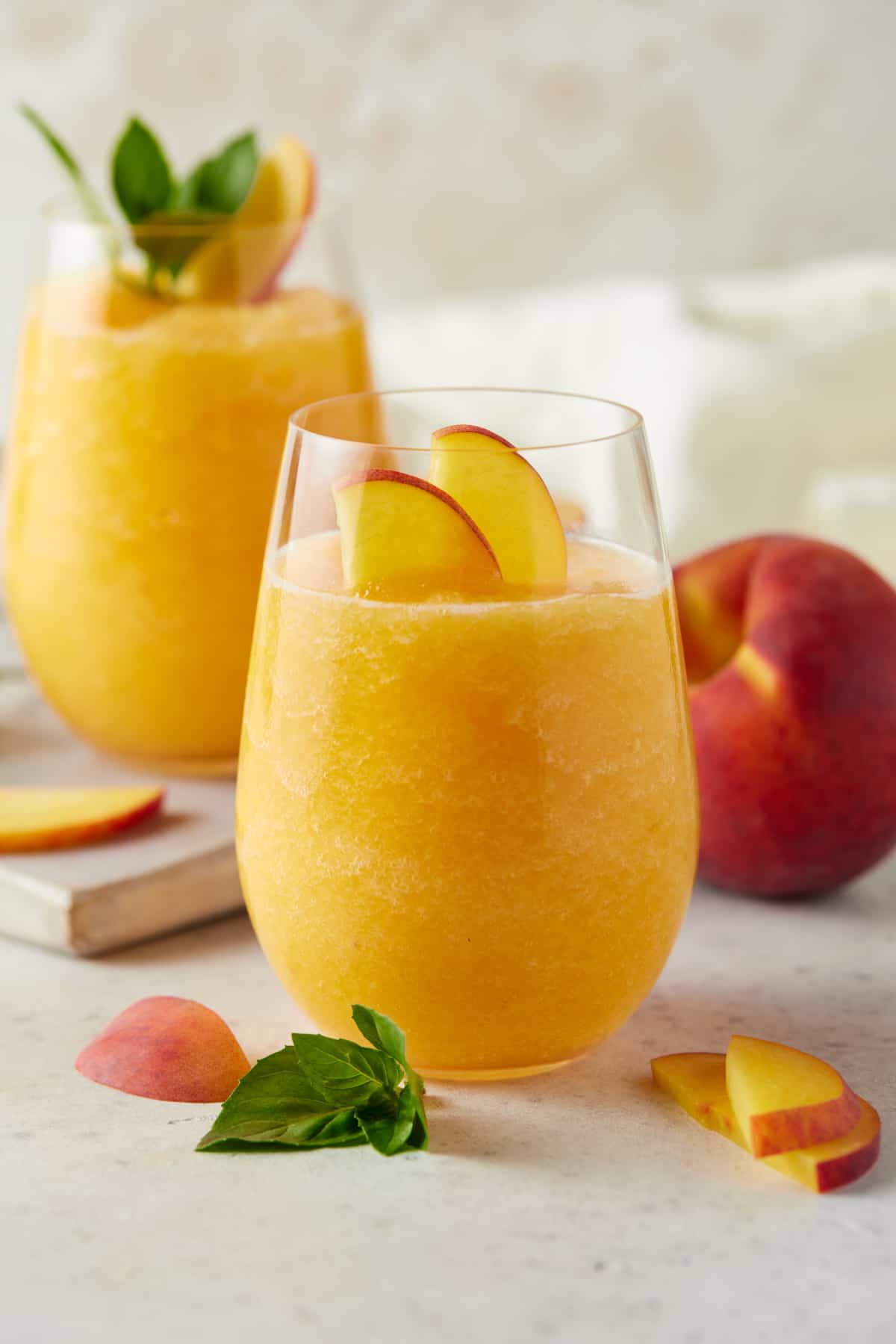 Stemless wine glass filled with peach wine slushy on white board. 