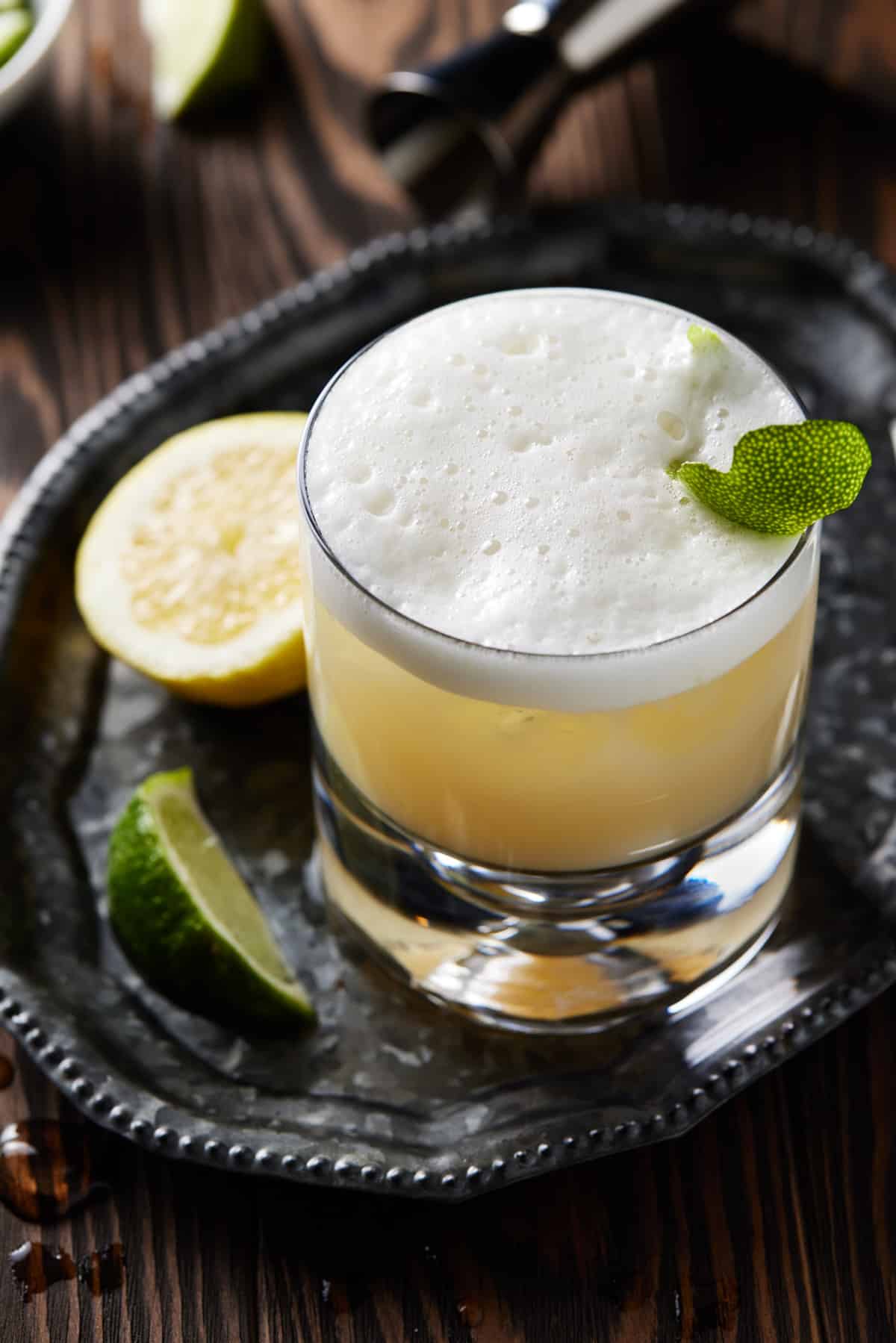Tequila sour on tray with lime wedge.