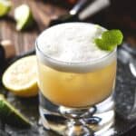tequila sour in glass with lime peel.