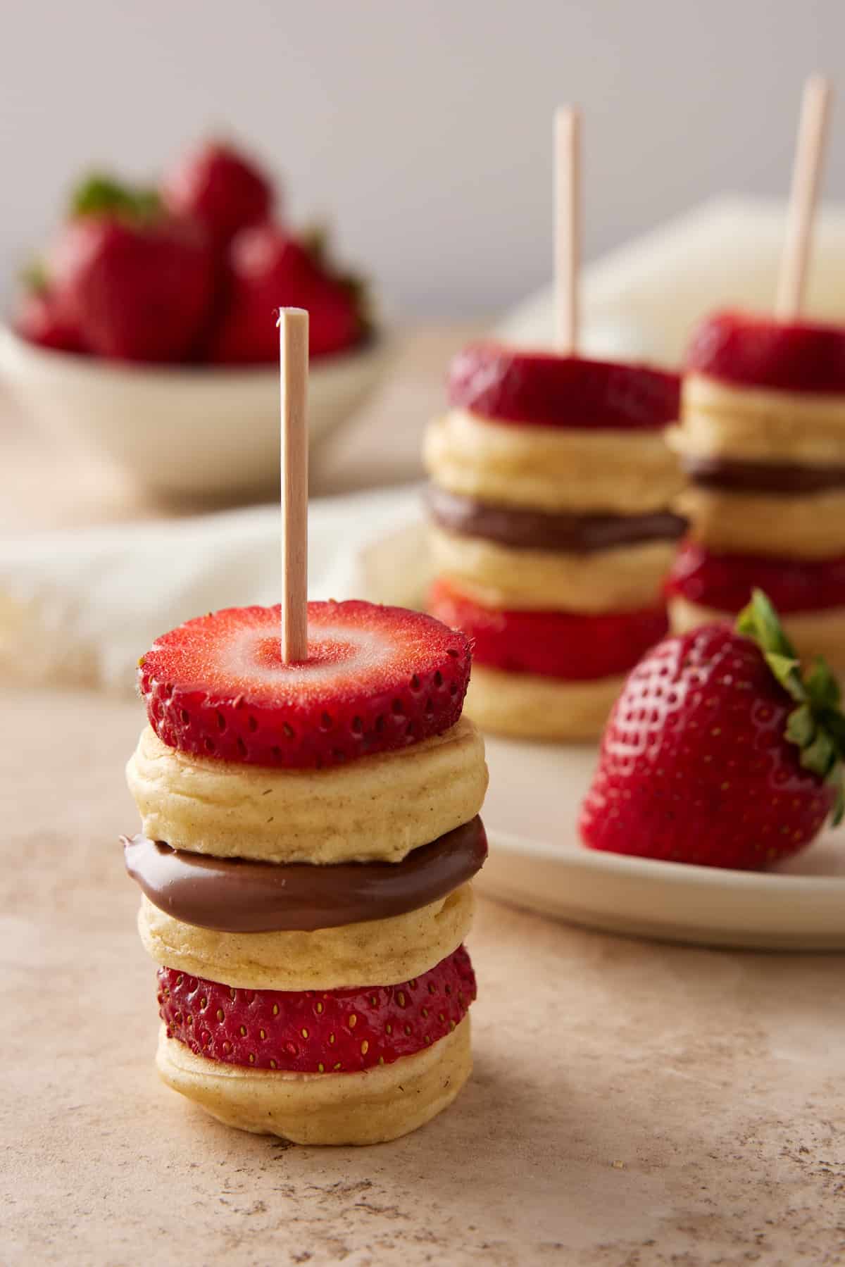 Mini pancakes layered with strawberry slices and Nutella and skewered with a toothpick. c