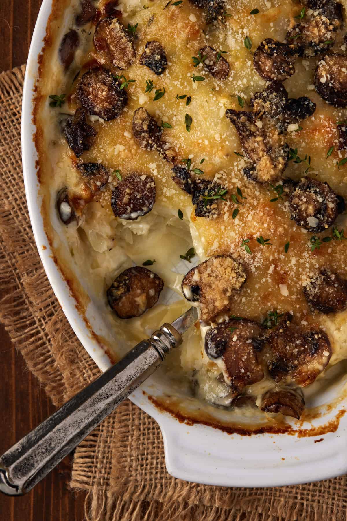 Spoon in a gratin dish with mushrooms and thyme with a scoop taken out.