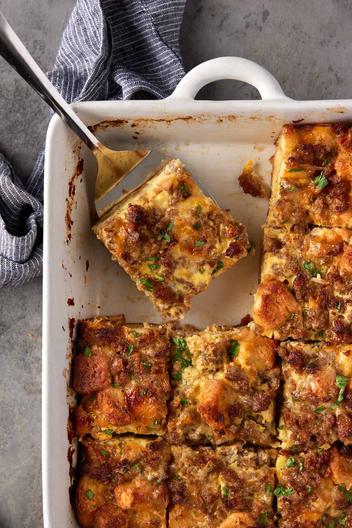 lifter holding a slice of egg casserole with sausage and cheese.