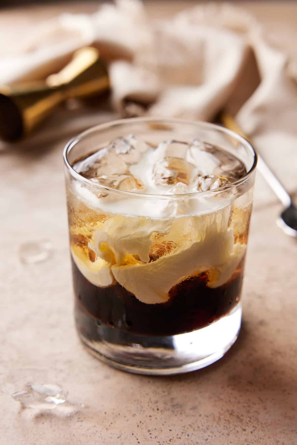 Lowball glass filled with ice, Kahlua and vodka with a layer of cream on top.