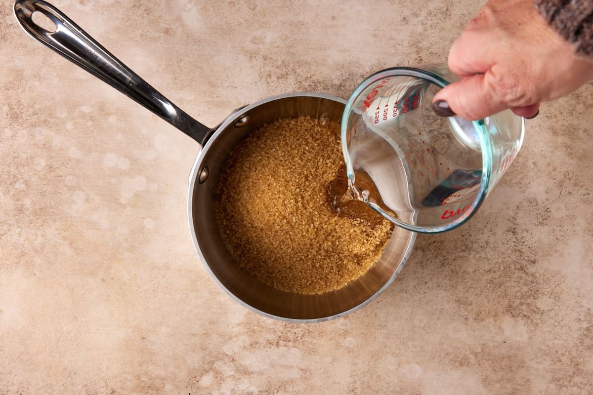 Water being poured over sugar in pan.