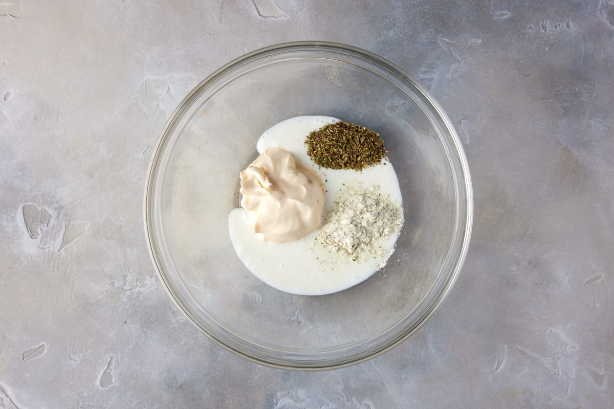 Buttermilk, mayo and seasonings in glass bowl.