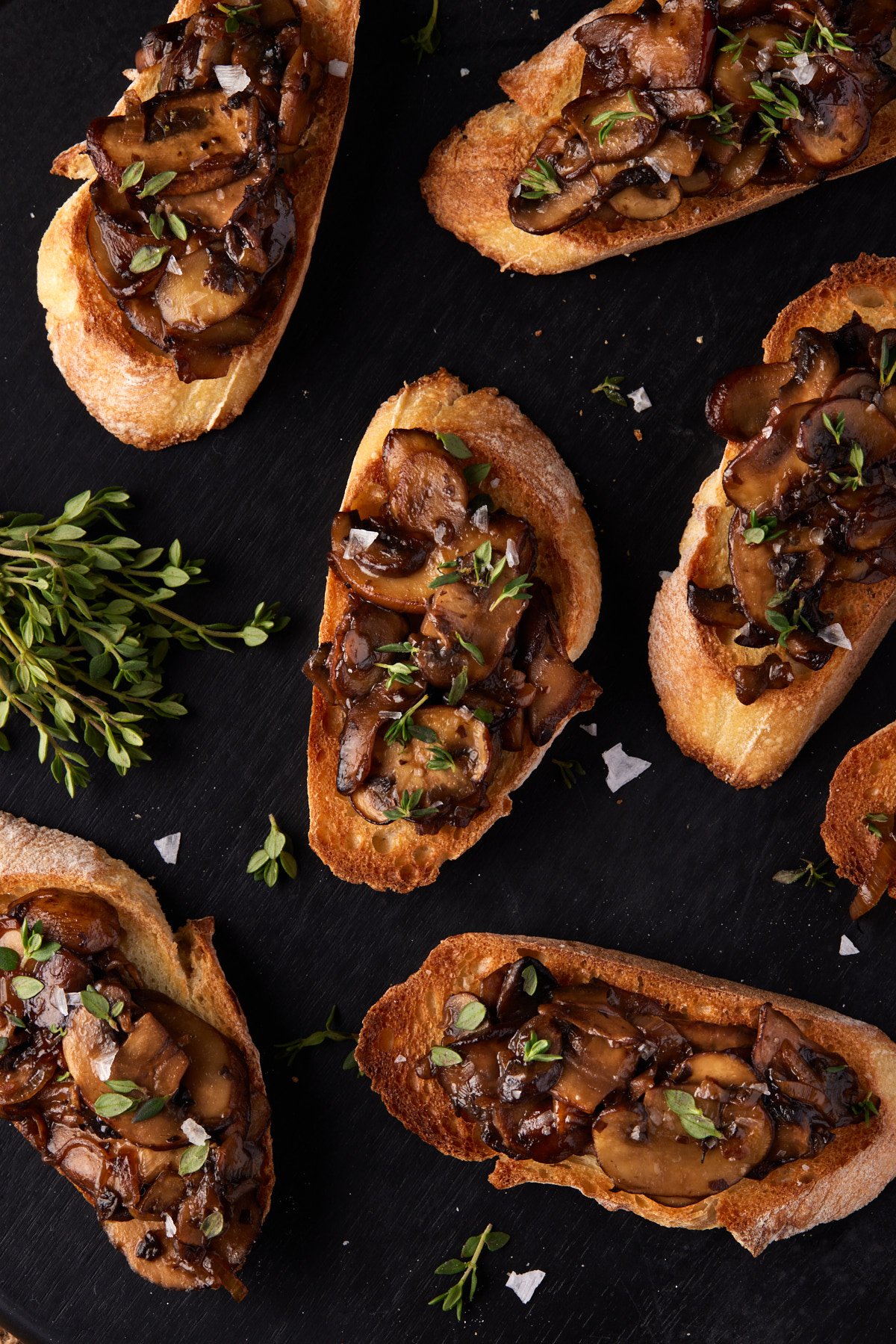 Close up shot of mushroom bruschetta on a black wood board. 