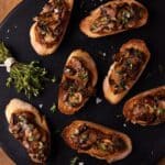 Black cutting board filled with mushroom bruschetta.