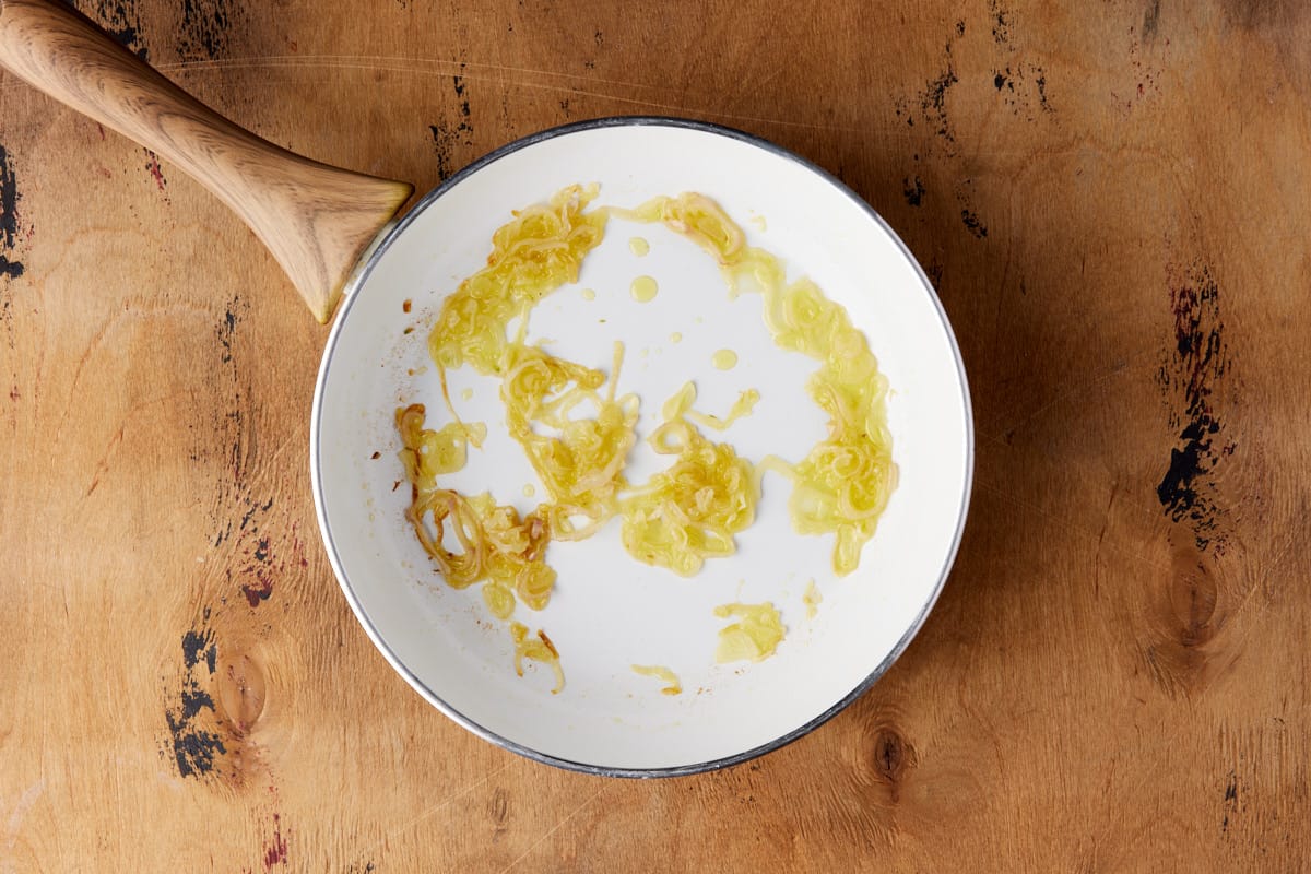 White skillet with sauteed shallots. 