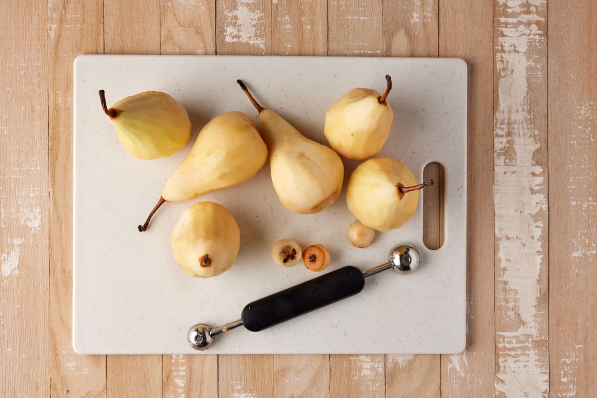 Peeled and cored pears on a white cutting board. 