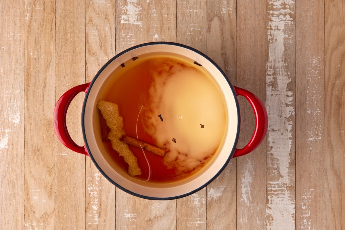 Poaching liquid ingredients in a red dutch oven. 