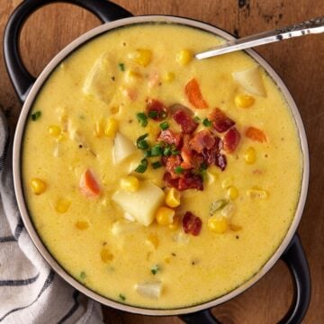 Bowl of potato corn chowder garnished with bacon and chives.