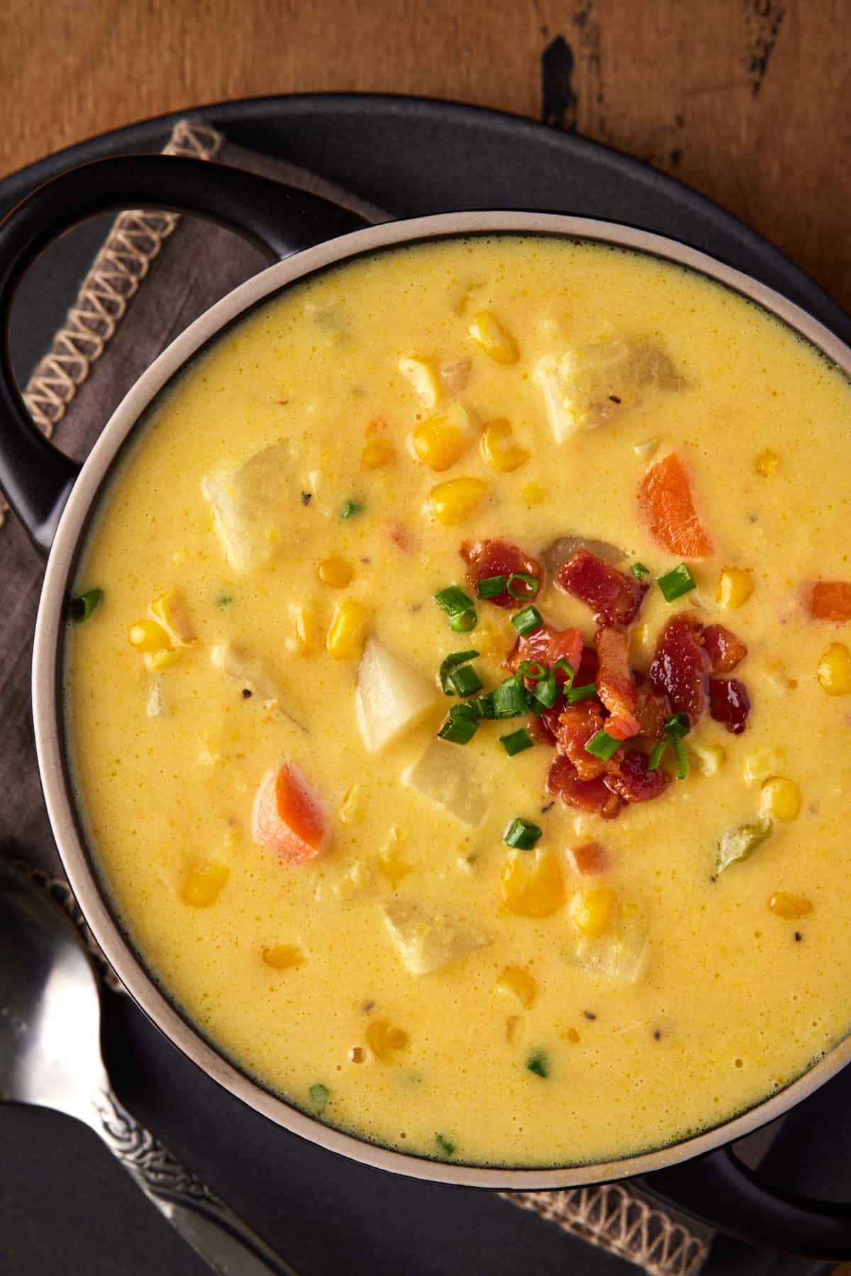 Black handled soup bowl filled with  potato corn chowder. 