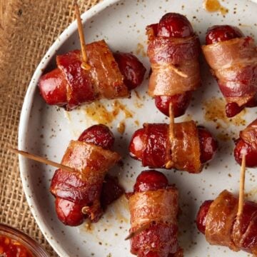 Bacon wrapped smokies with toothpicks on a cream plate.