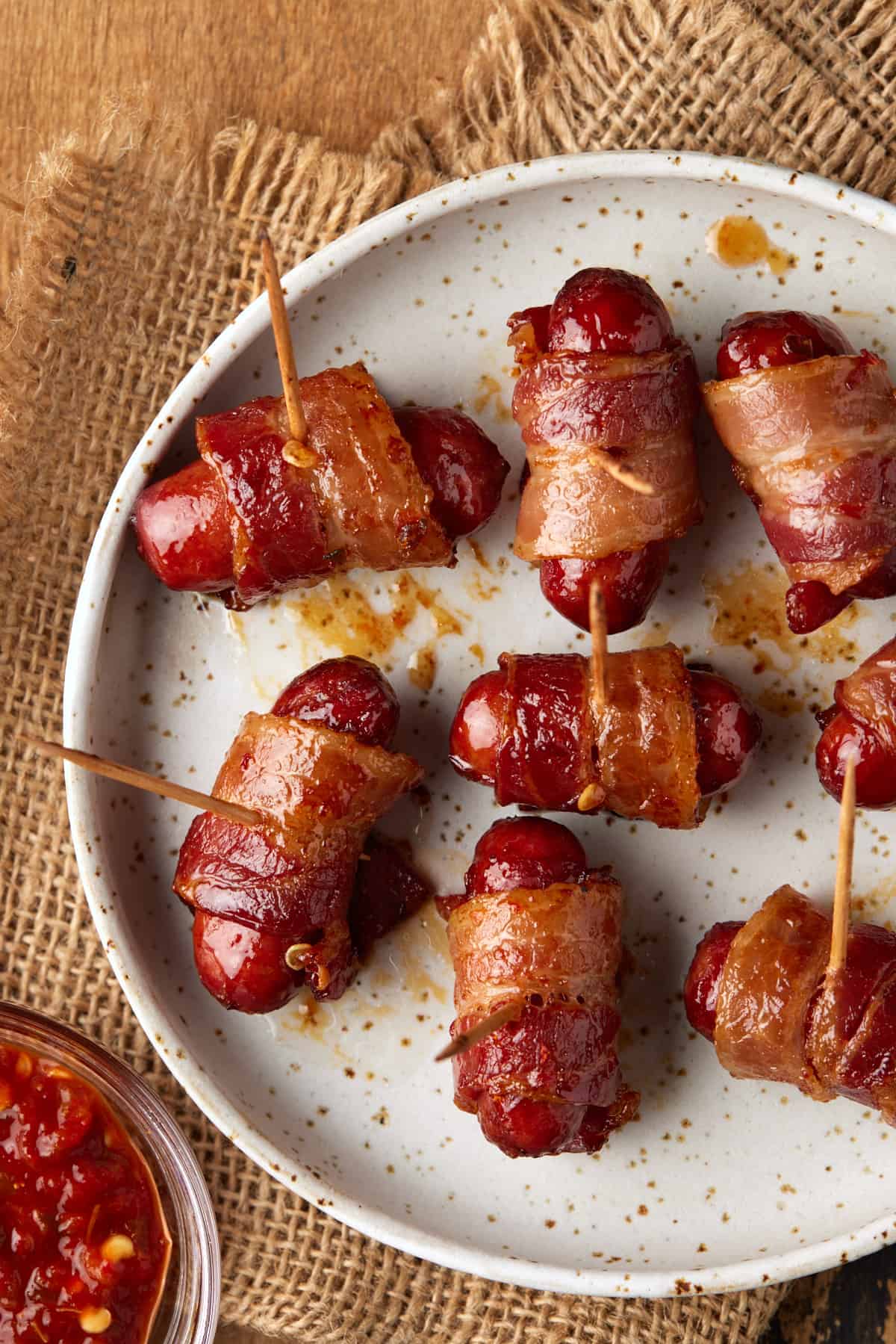 Bacon wrapped little smokies on a cream speckled plate. 