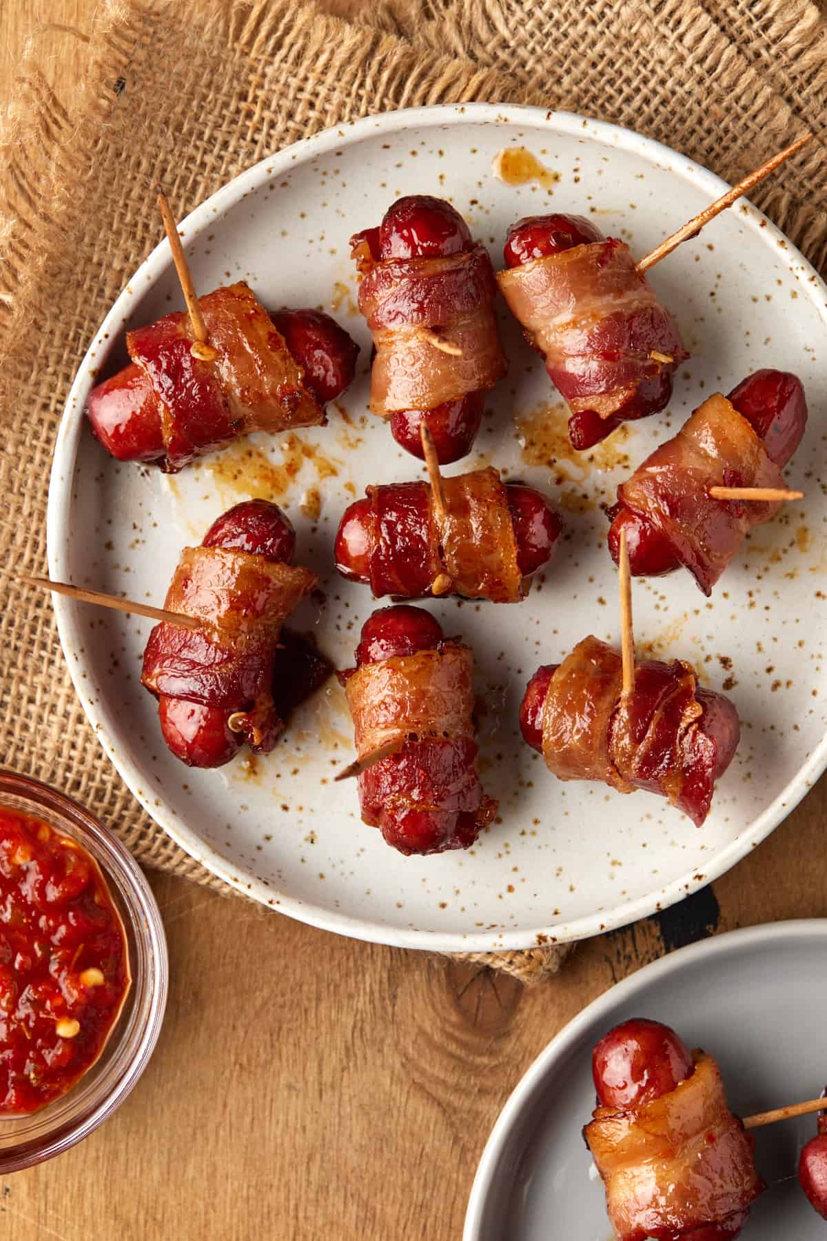 Two plates filled with bacon wrapped little smokies. 