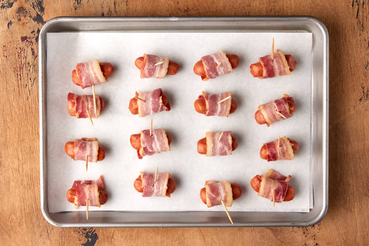 Little smokies wrapped with bacon on a sheet pan. 