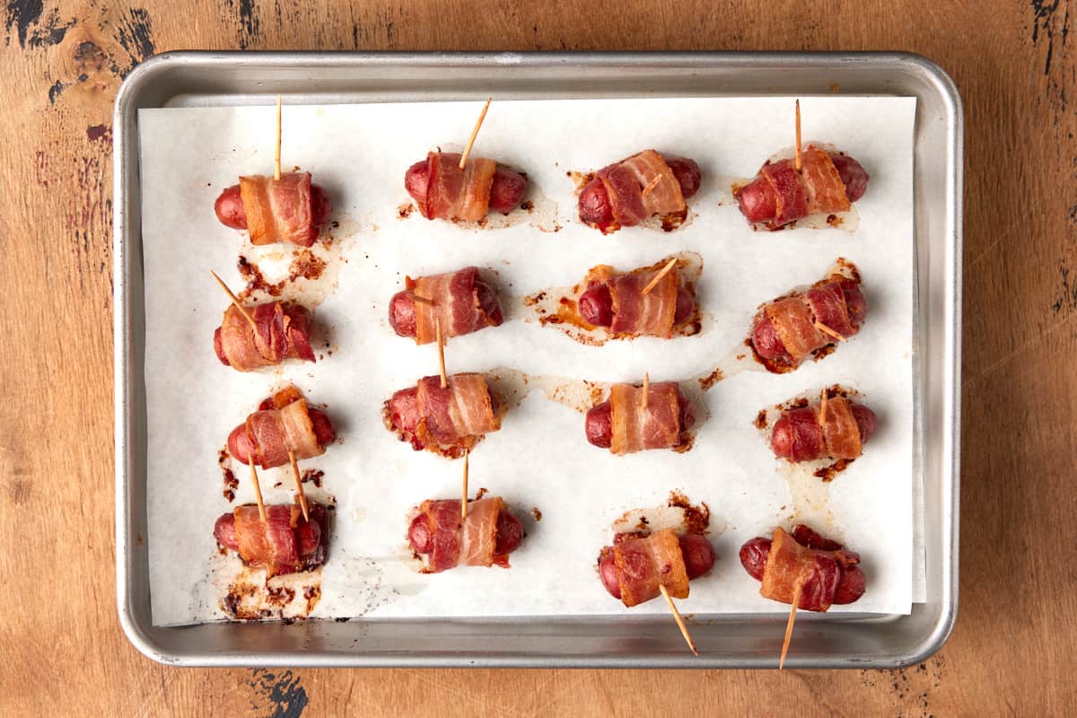 Baked little smokies wrapped in bacon on sheet pan. 